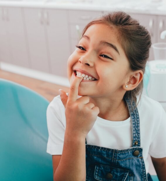 Child pointing to smile after visiting dentist who accepts Medicaid for children
